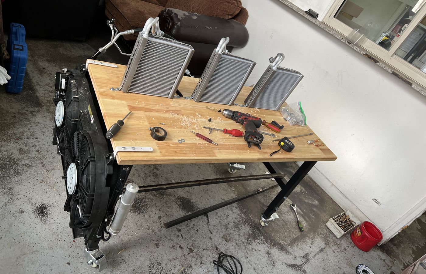 The workbench with three coils mounted on top, the condenser and fans on the front, and tools spread across the top