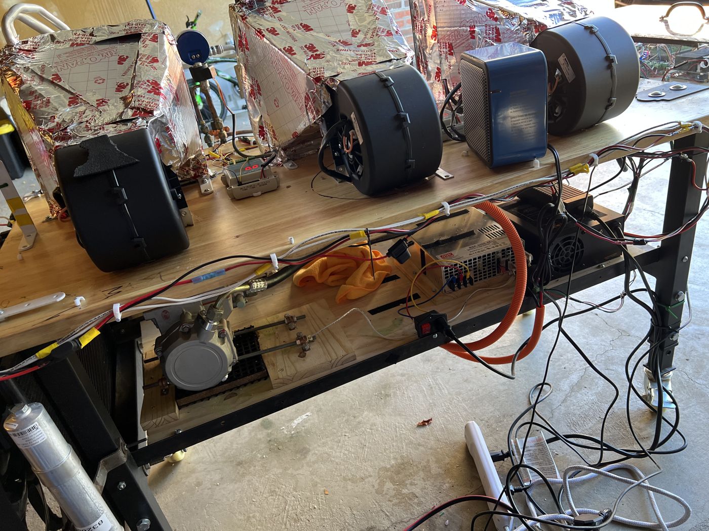 Close view of the rebuilt bench: blowers on top and the compressor and power supply mounted underneath