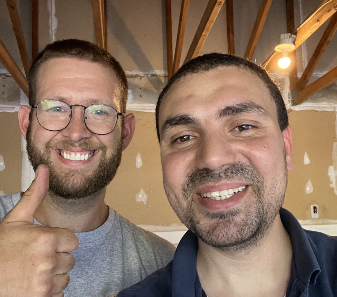 Ahmed and the AC technician smiling together in the garage